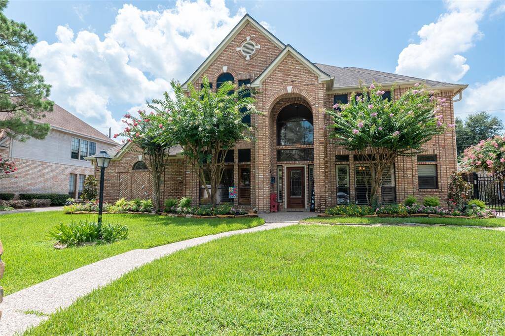 This beautiful two-story home features a classic brick exterior. It includes a spacious two-car detached garage and a well maintained front yard with lush greenery, offering great curb appeal.