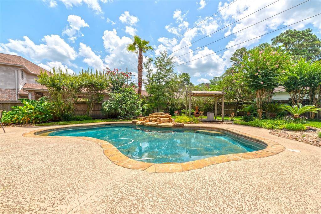 Spacious backyard features a sparkling pool with a tranquil waterfall feature, perfect for relaxing or entertaining.