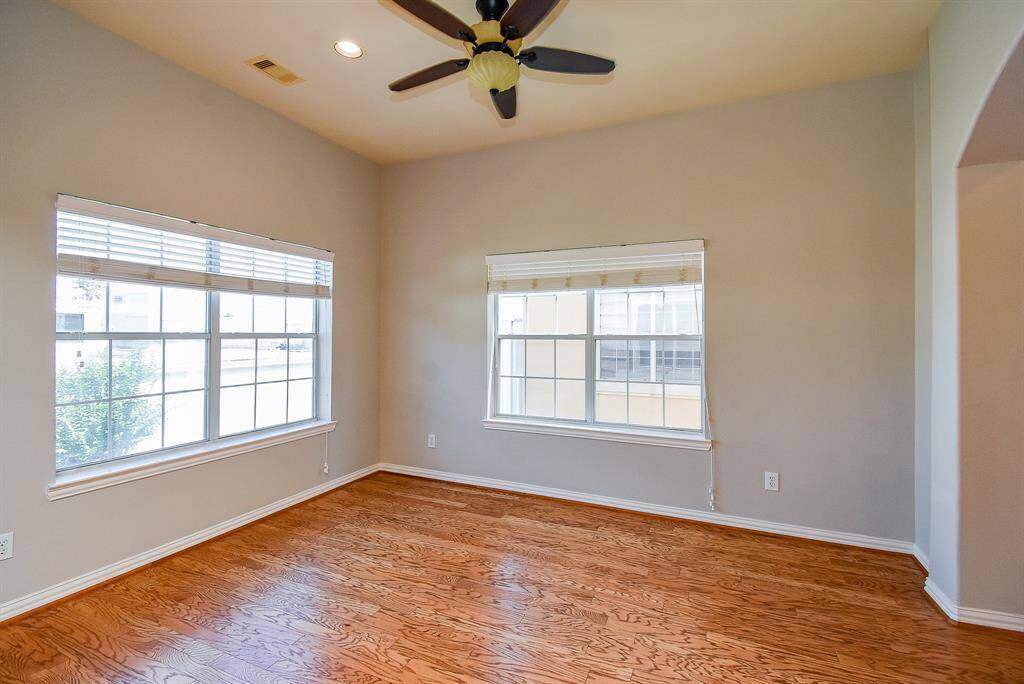 This inviting space features hardwood floors and abundant natural light from a large window. An elegant arched entryway leads to a staircase, adding charm and depth to the room.