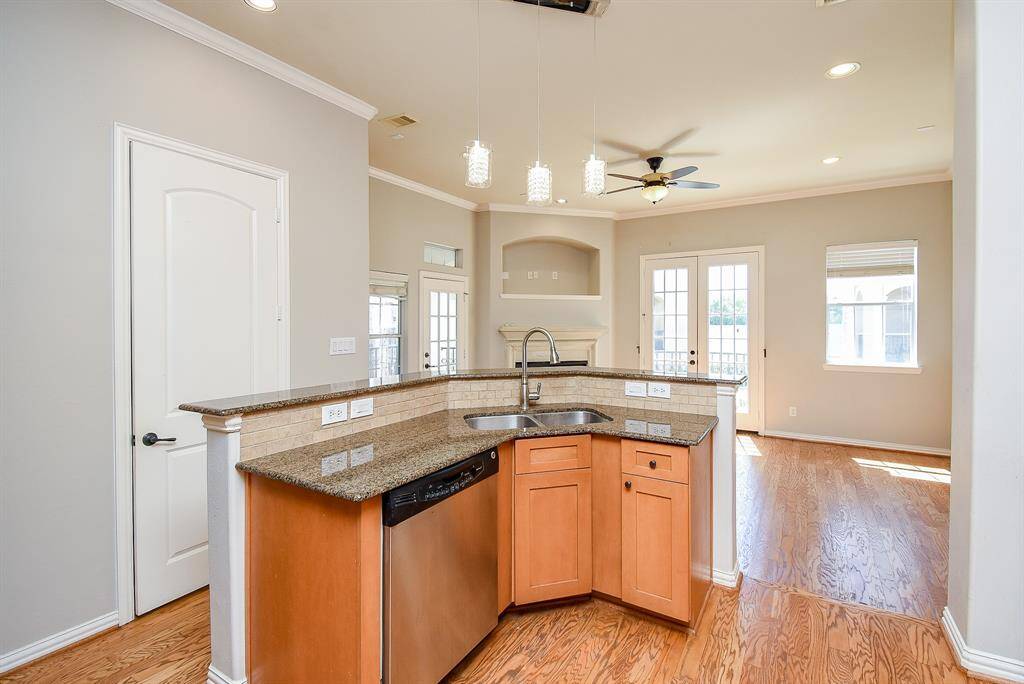 The kitchen ?breakfast bar offers additional seating, and the room is well-lit with natural light from large windows and French doors leading to a balcony.