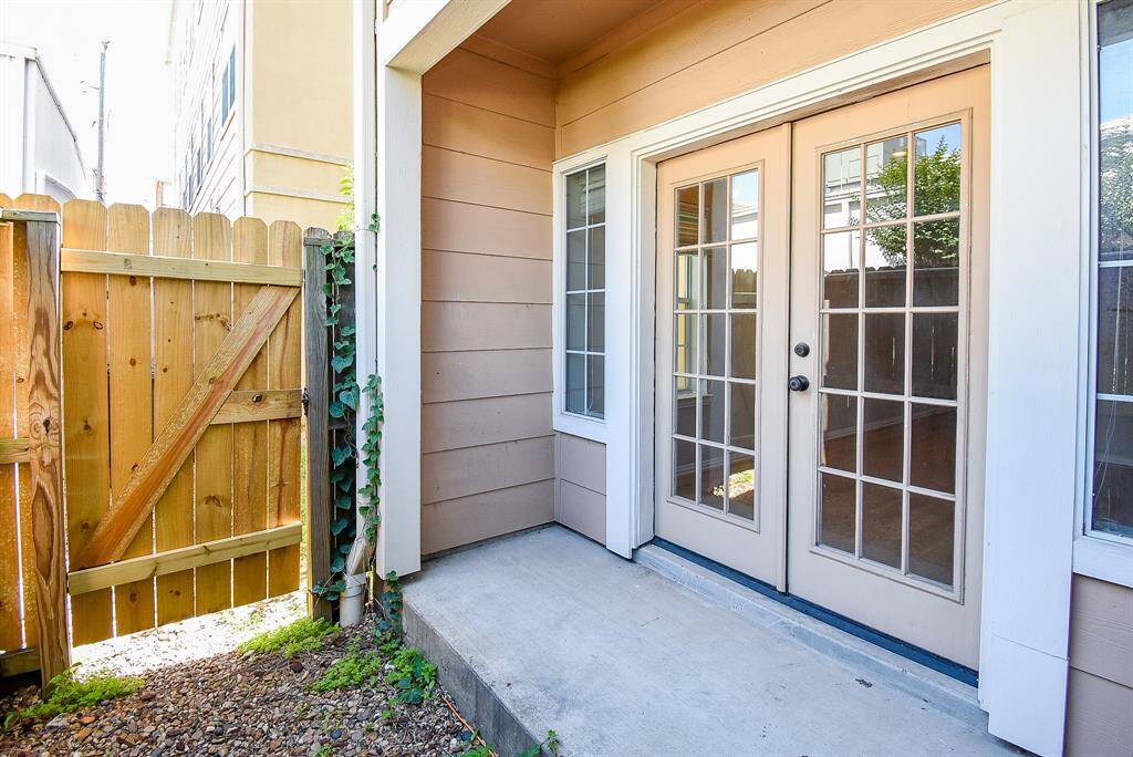 This photo shows the balcony with tiled flooring and a glass-paneled door. It features a metal railing and is attached to a stucco exterior wall, offering a cozy outdoor space with a view.