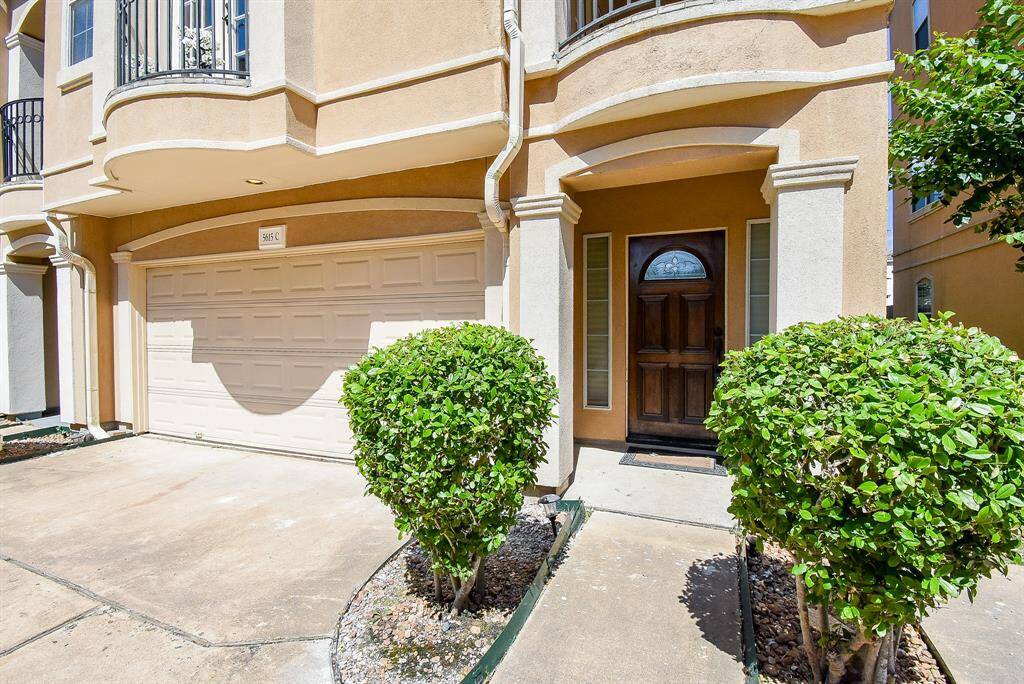 This entryway features a wooden front door with decorative glass, flanked by narrow windows. The staircase has elegant wrought iron spindles and a wooden handrail, complemented by light wood flooring and neutral wall colors.