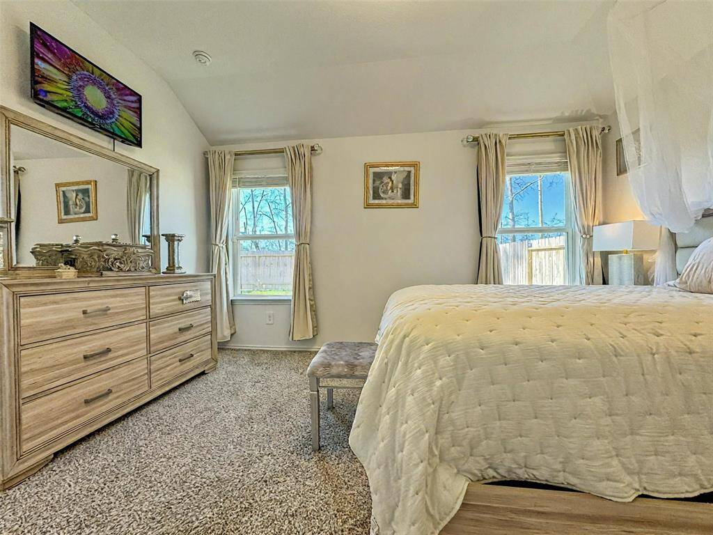 Primary bedroom. Natural light streams in through two windows adorned with elegant curtains, creating a bright and inviting space.