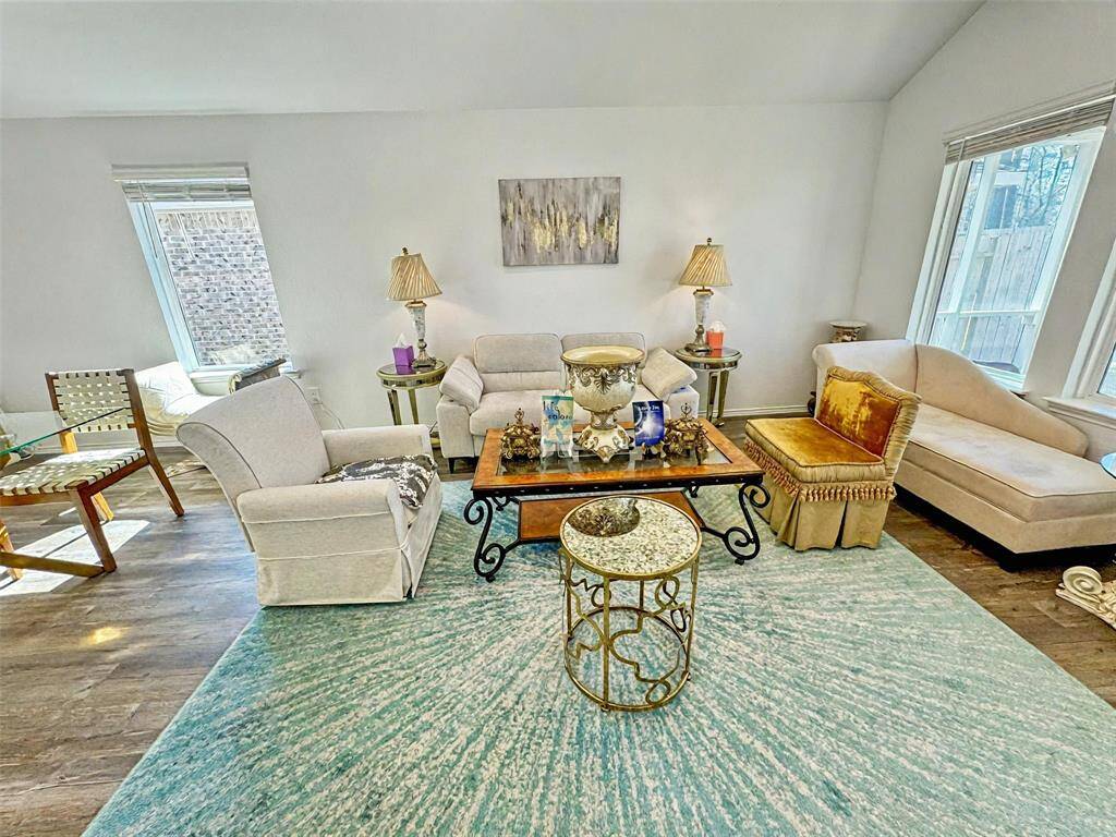 Bright and inviting living room with large windows, and a cozy seating area. The space features a blend of modern and classic decor, highlighted by elegant lighting.