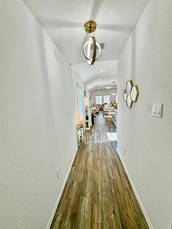 Bright and welcoming entryway with modern light fixture, wood-style flooring, and stylish decor accents.