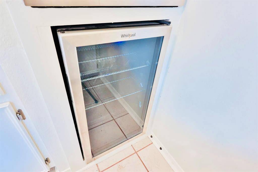 This photo shows a built-in beverage cooler with a glass door, integrated into a kitchen space. The cooler has a sleek design, ideal for storing drinks conveniently.