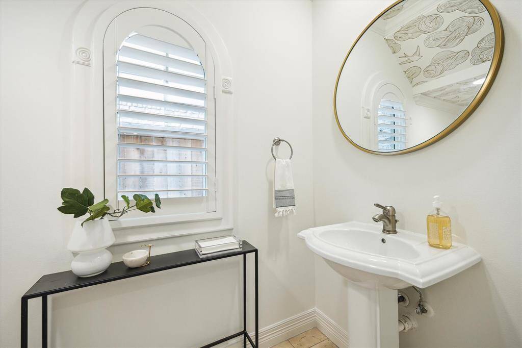 [Powder Bath] Secluded just off the entry hall, the spacious powder bath has a pedestal sink, and wallpaper adds dimension and warmth to the space.