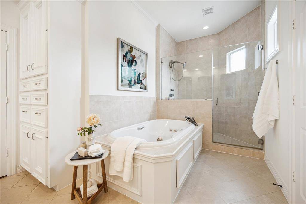 [Primary Bath] Marble counters; whirlpool tub with stone deck and surround; frameless shower and a water closet with door.
