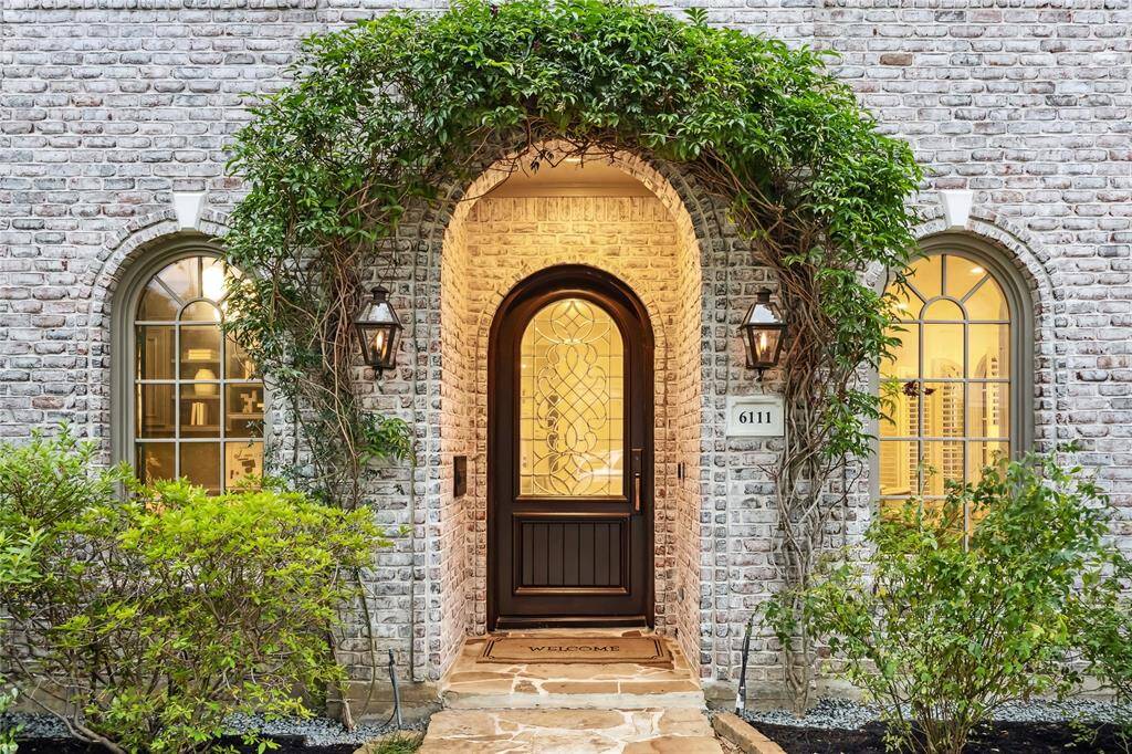 Charming arched and elegant entry - framed by climbing vines and natural gas coach lanterns.