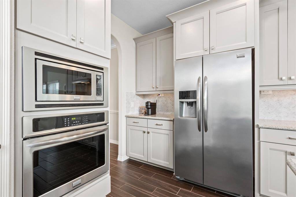 Beyond the main kitchen footprint is an ideally located cabinet set that creates a butlers pantry-style transition as you head into the dining room. This space is currently being used as a coffee bar by the current owners. A built-in wall oven and microwave complete the appliance suite in this kitchen, which has abundant countertop  and cabinet space for all of your kitchen essentials.