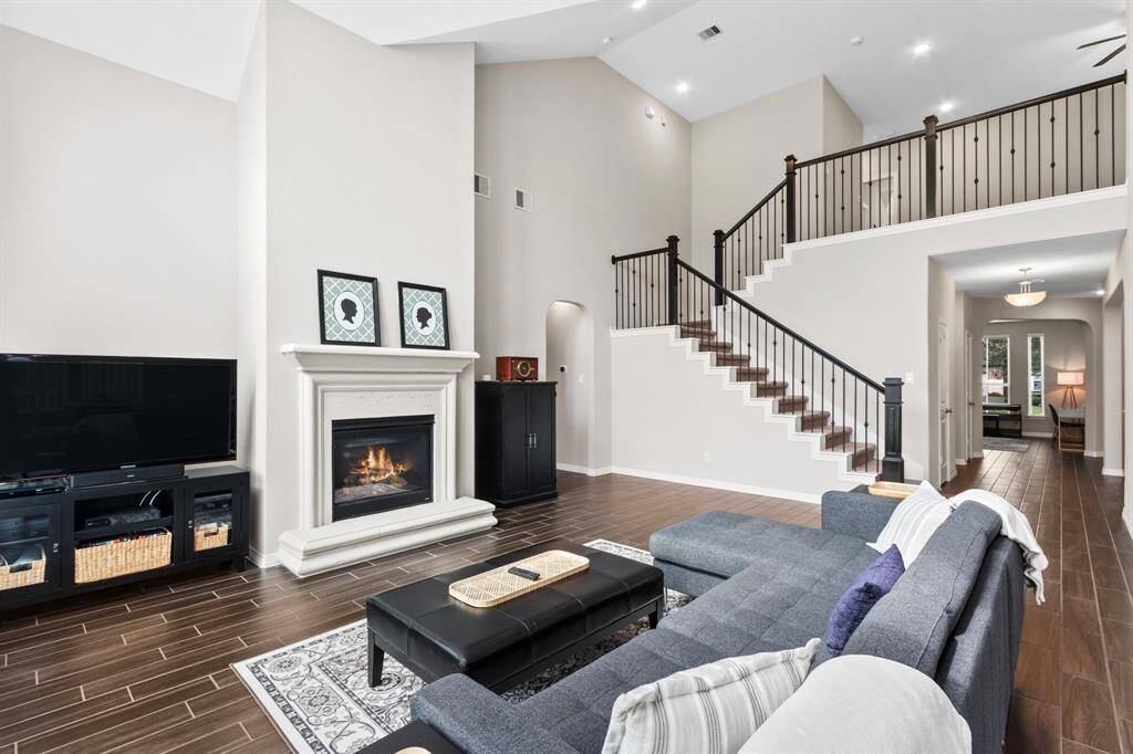 Enjoy views of the backyard and to the front of the home from the comfort of your couch or favorite chair. The gas fireplace with stone hearth and mantle makes a statement, and adds an elevated touch to this relaxing space in the heart of your home. The wrought iron balusters on the stairs take a functional piece of construction and turn it into an impressive design feature.