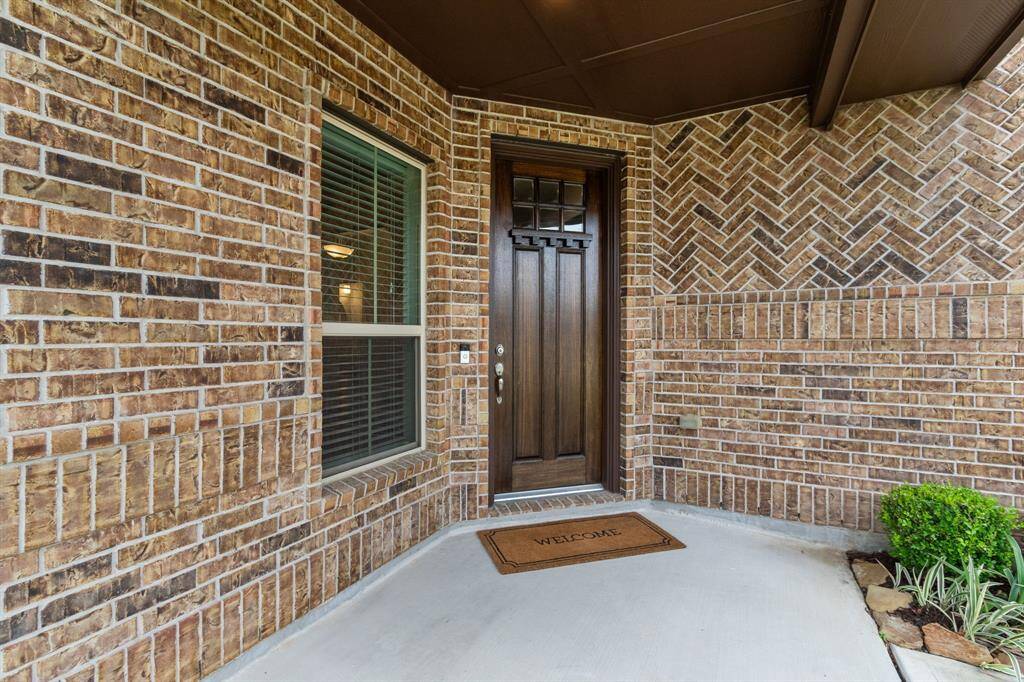 Herringbone brick work and the offset solid-wood front door add visual interest to the front elevation of the home, while the covered entry porch provides a comfortable space to visit with neighbors or receive package deliveries in any kind of weather.