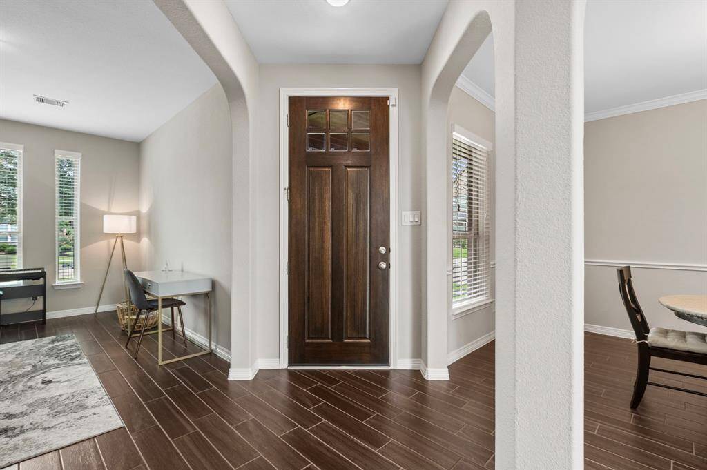 Gleaming hardwood floors set the tone as you enter the front doo and are immediately struck by the relaxed and neutral color scheme and consistent architectural themes, like the twin arched entries to the office/den (seen to the left) and dining room (to the right), both infused with natural light and views of the front landscaping.