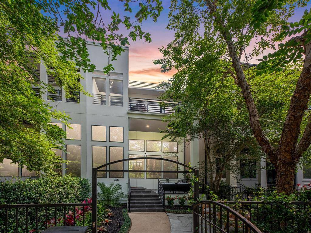 Modern 3-story home with a sleek exterior, large windows, and 3 spacious balconies. Surrounded by lush trees and well-maintained landscaping, it features a gated entryway with a welcoming path.