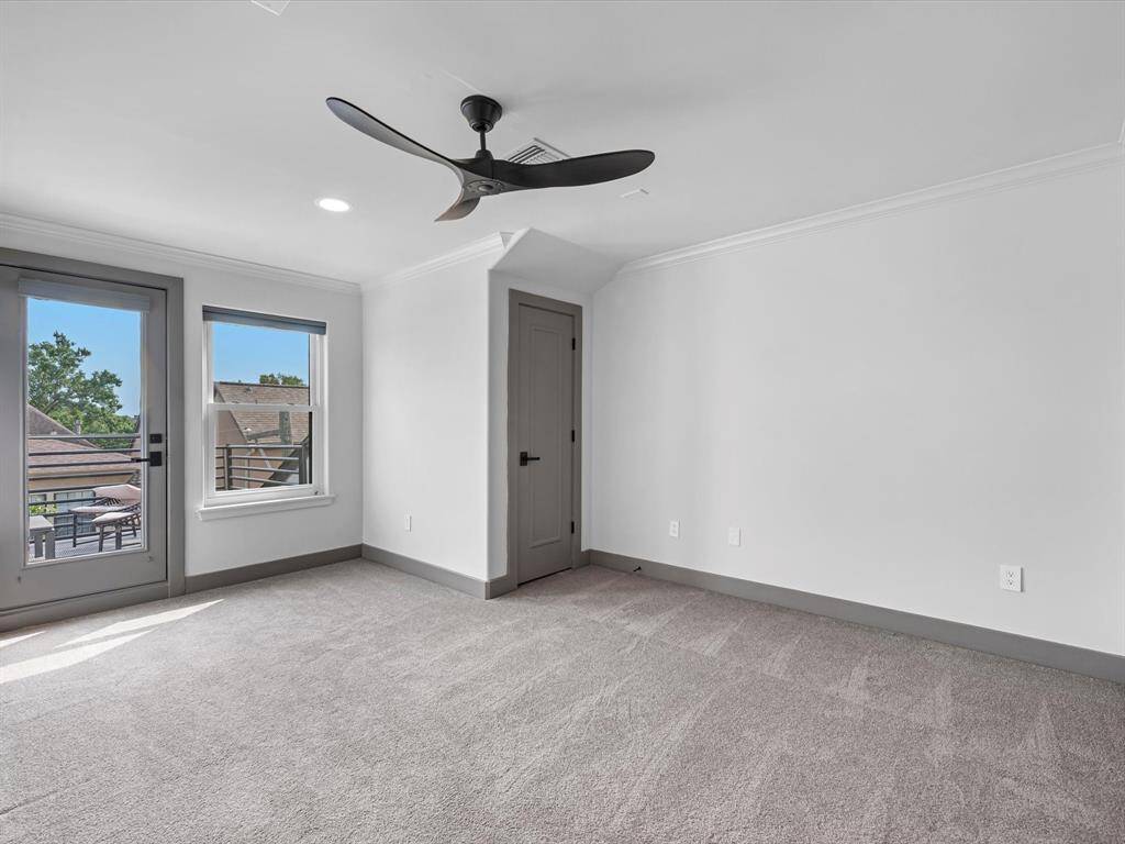Bedroom 3 is another spacious room with carpet flooring, and features a modern ceiling fan. It has large windows and a glass door leading to a balcony, offering plenty of natural light and a pleasant view.