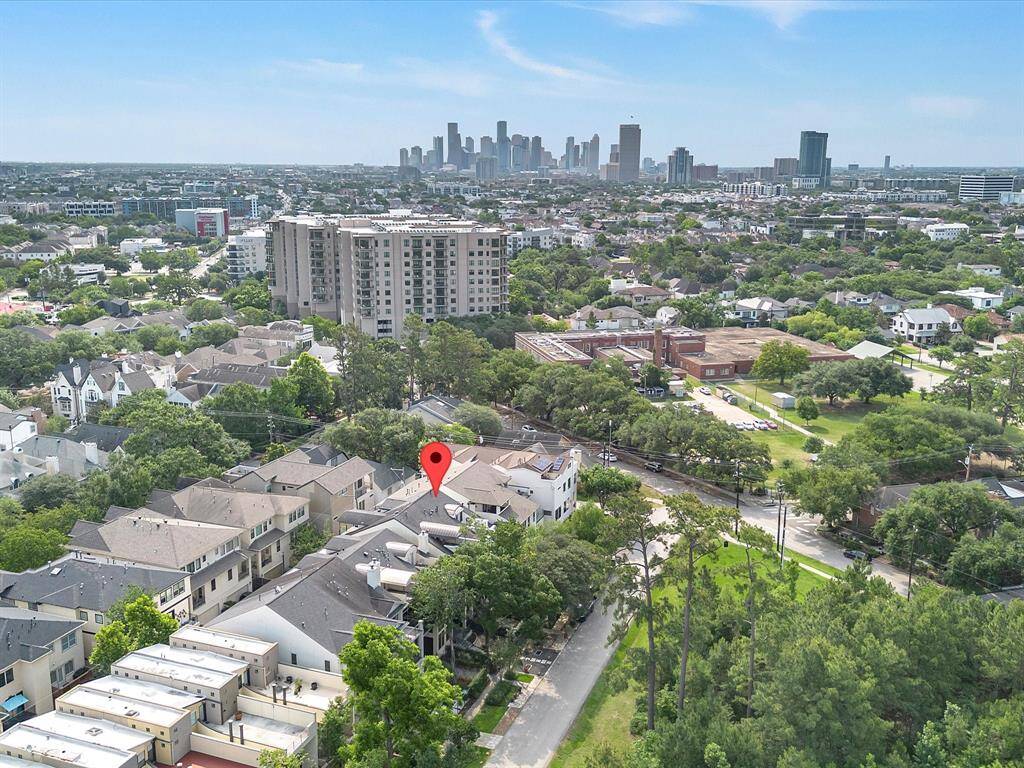 This photo showcases the residential neighborhood with tree-lined streets, surrounded by greenery. The area is characterized by modern homes and townhouses, and is conveniently located near Downtown, visible in the background.