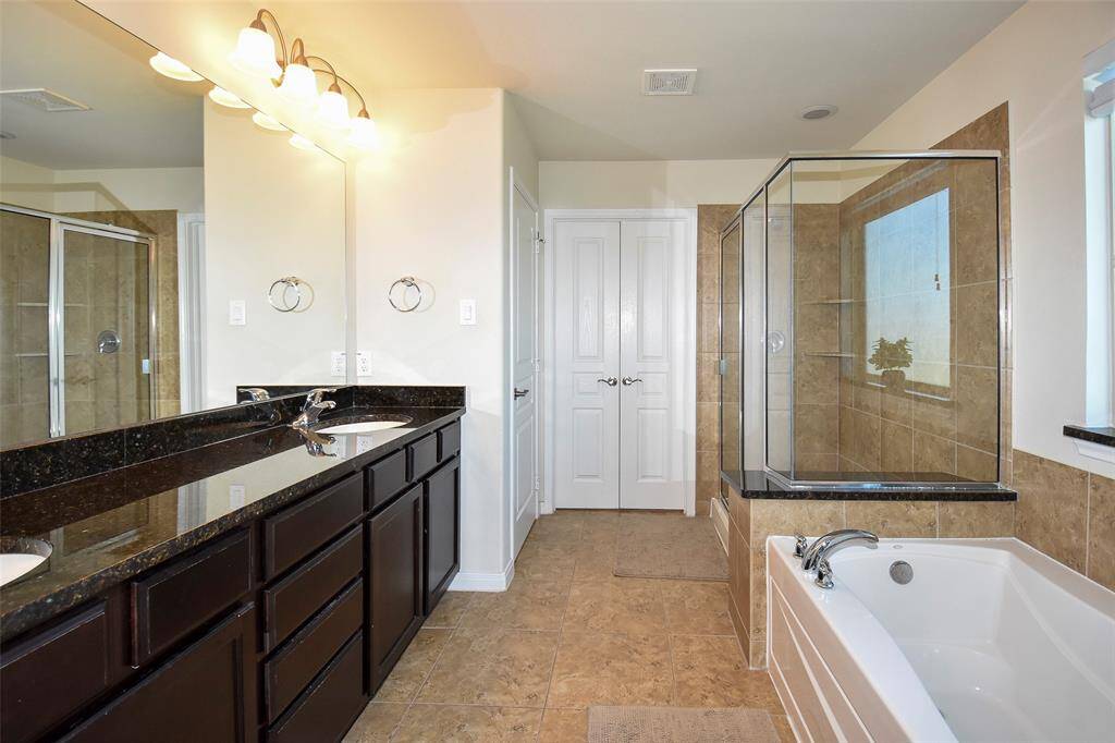 Primary  bathroom with granite countertops, double sinks, tub, separated shower and walk-in closet.