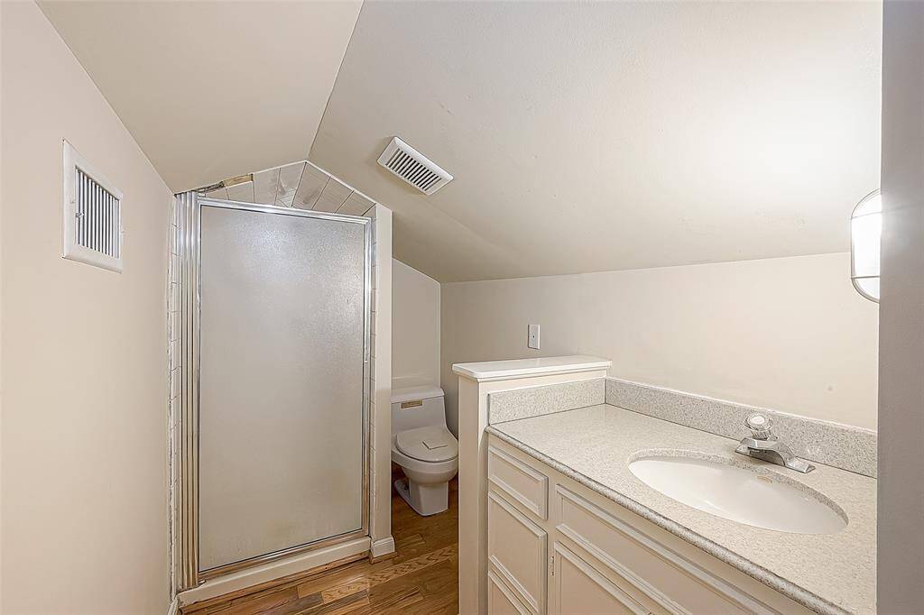 The bathroom is nicely functional and includes a sink with storage, toilet, and tiled shower.