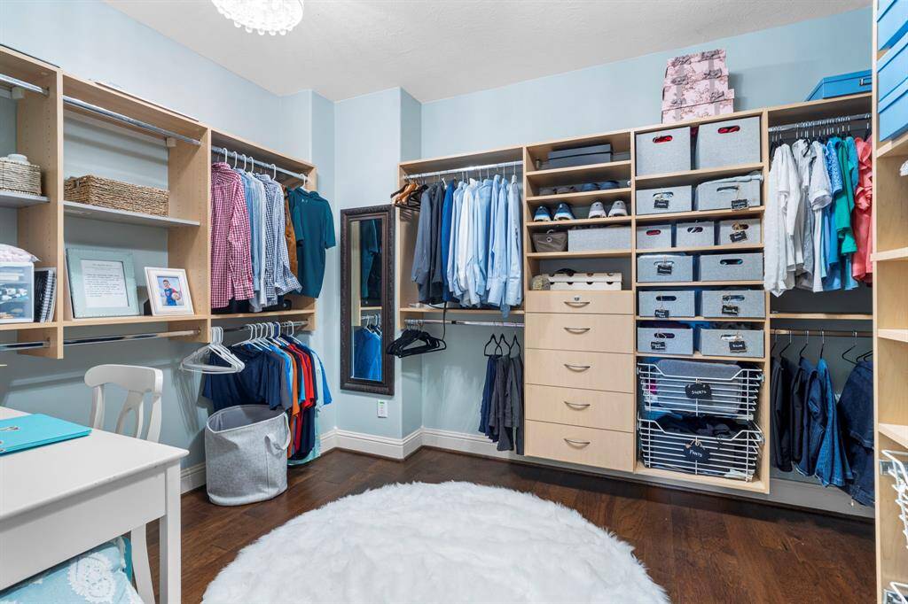 The primary walk-in closet features built-in shelving and plenty of storage space.