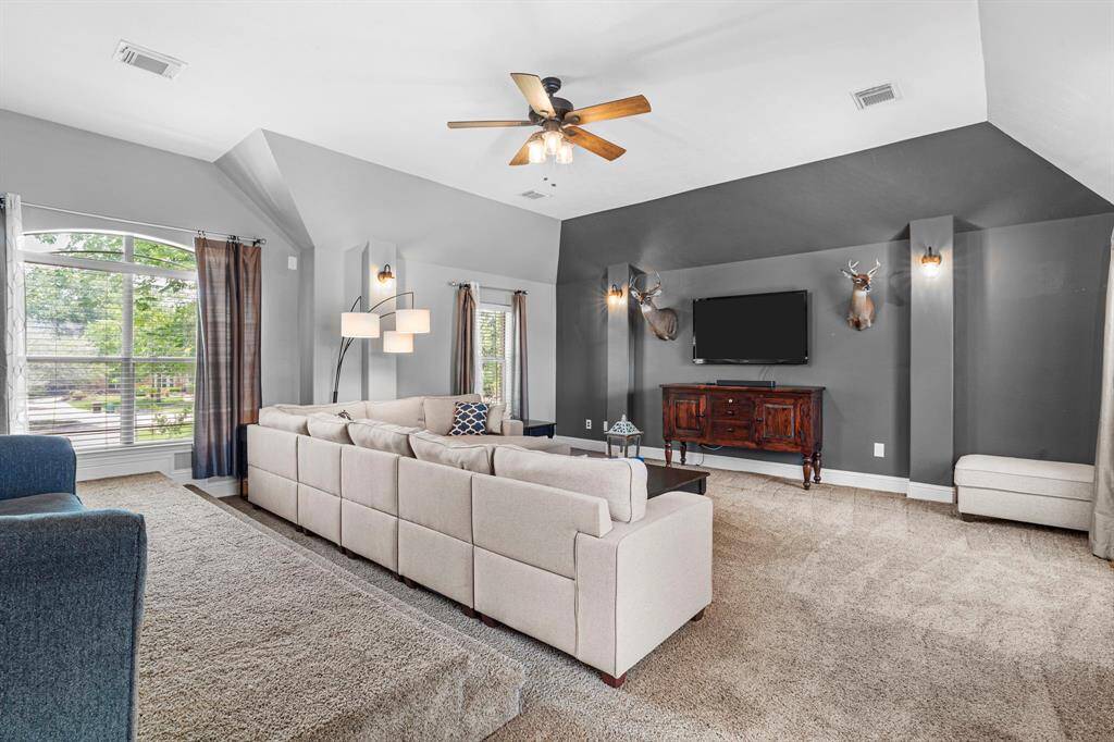 The media room features plush carpet, custom paint, high ceilings, and large windows.