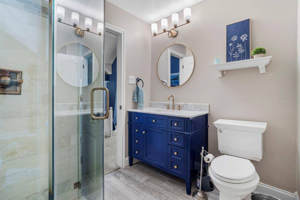 Secondary bathroom features a walk-in shower and blue vanity.