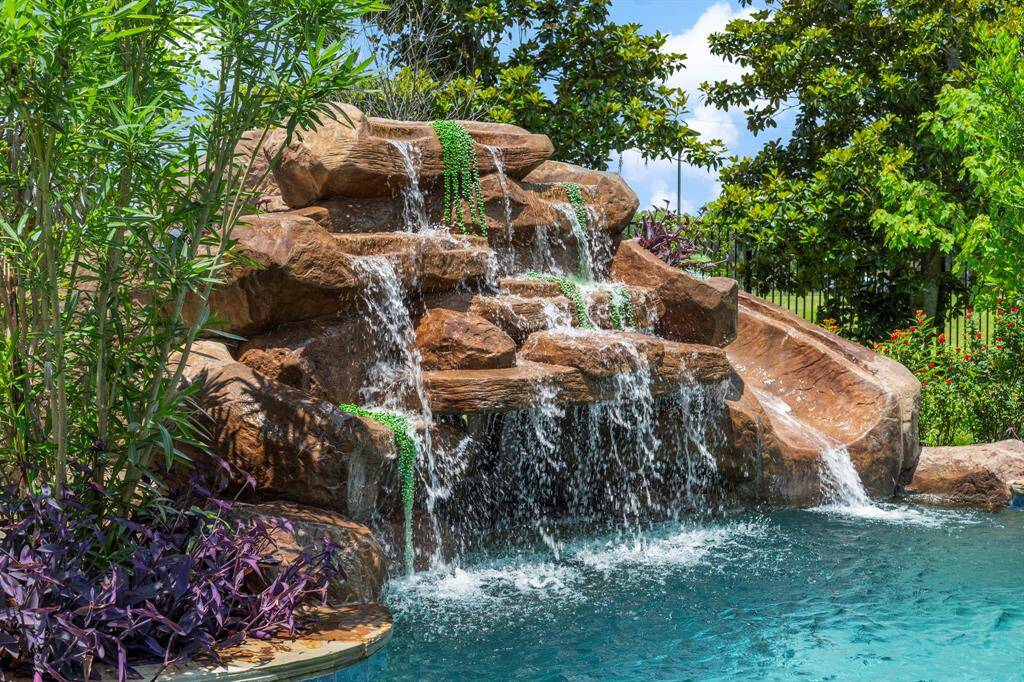 The backyard has a waterslide and relaxing waterfall into the pool.