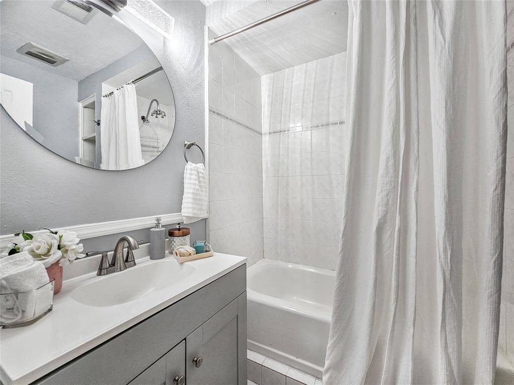 Secondary bathroom with plenty of lighting, storage, and sower/tub combo