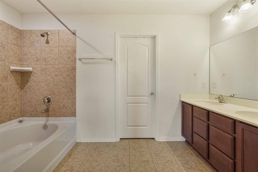 Master bath with tile floors, dual sinks, and a shower/tub combo.