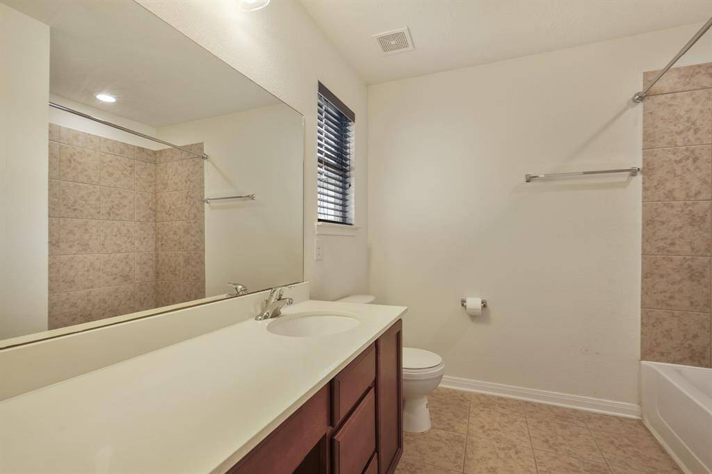 Secondary bath with a shower tub combo, a large mirror, and vanity area.