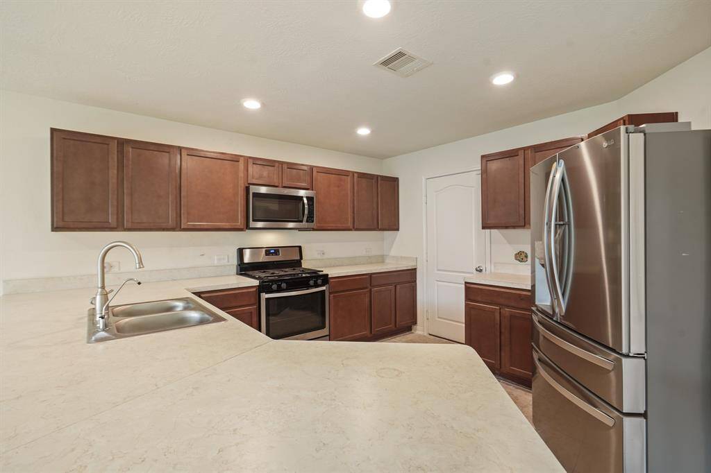 This kitchen has genereous space! It has recessed lighting, wooden cabinetry, stainless steel appliances, and plenty of counterspace.