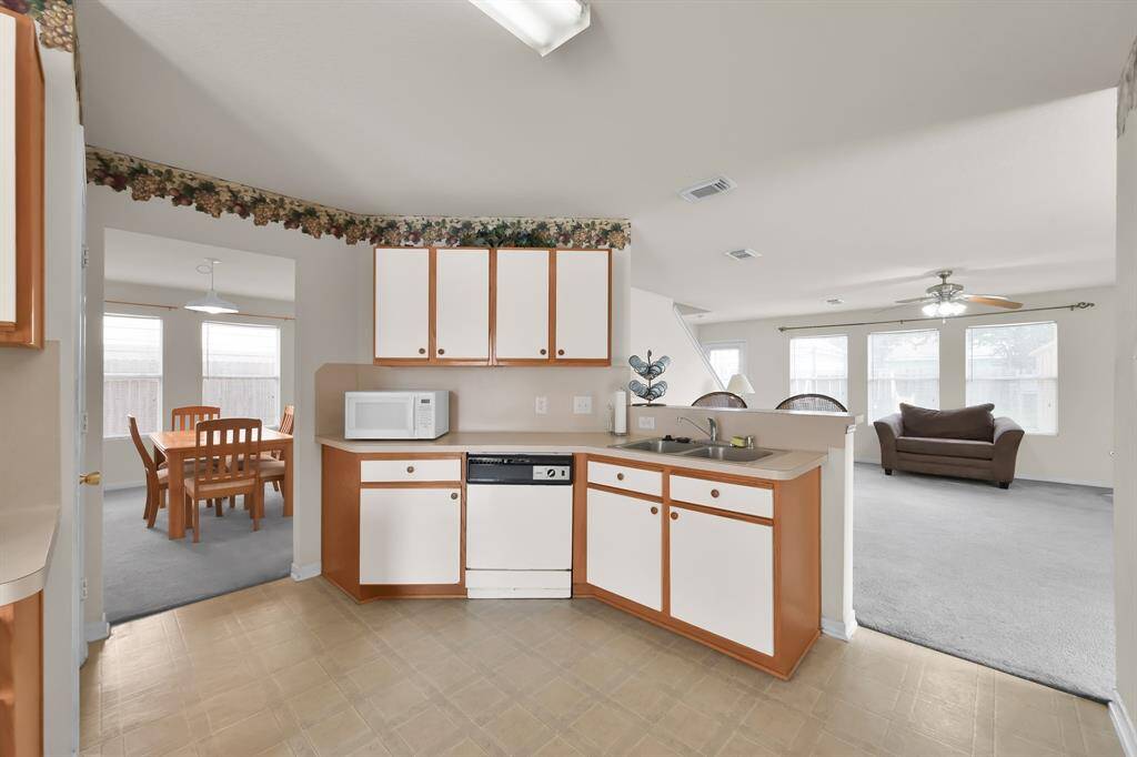 Beautiful and large kitchen featuring white cabinets and offering views of the living room and breakfast nook