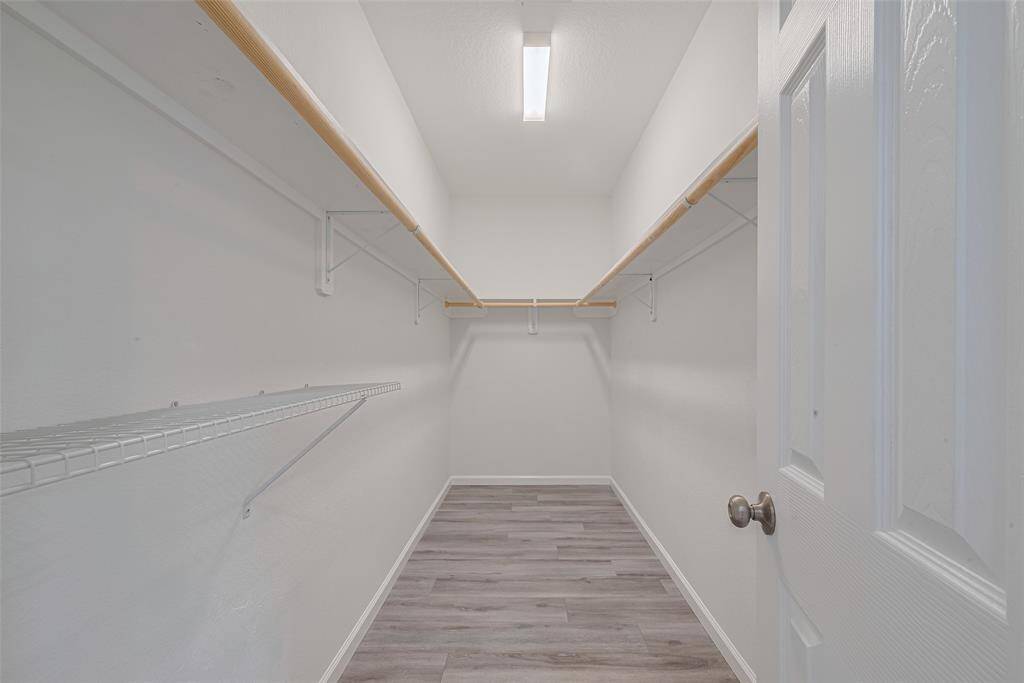 Spacious walk-in closet with ample shelving and hanging space, featuring bright lighting and a clean, modern design.