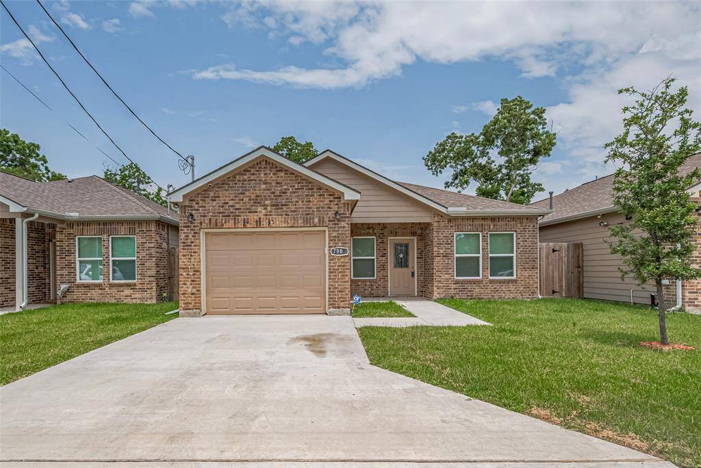 Charming single-story brick home with a neatly manicured lawn. The driveway and pathway lead to a welcoming entrance surrounded by windows that allow natural light inside. This home is ideal for a cozy living space.