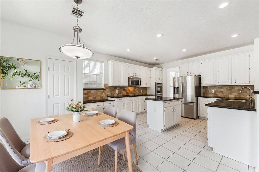 BRIGHT BREAKFAST AREA WITH TILE FLOORING, MODERN LIGHT FIXTURE, AND LARGE WINDOW OVERLOOKING THE SIDE YARD — PERFECT FOR MORNING COFFEE. **This room has been virtually staged