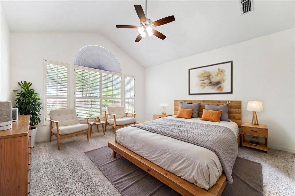 SPACIOUS PRIMARY BEDROOM WITH VAULTED CEILINGS, DESIGNER CEILING FAN, AND A LARGE ARCHED WINDOW WITH PLANTATION SHUTTERS. **This room has been virtually staged.