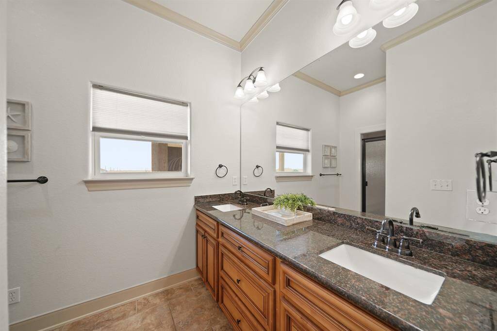 The ensuite bath includes a granite double vanity, framed mirror, and soft lighting—both stylish and practical.