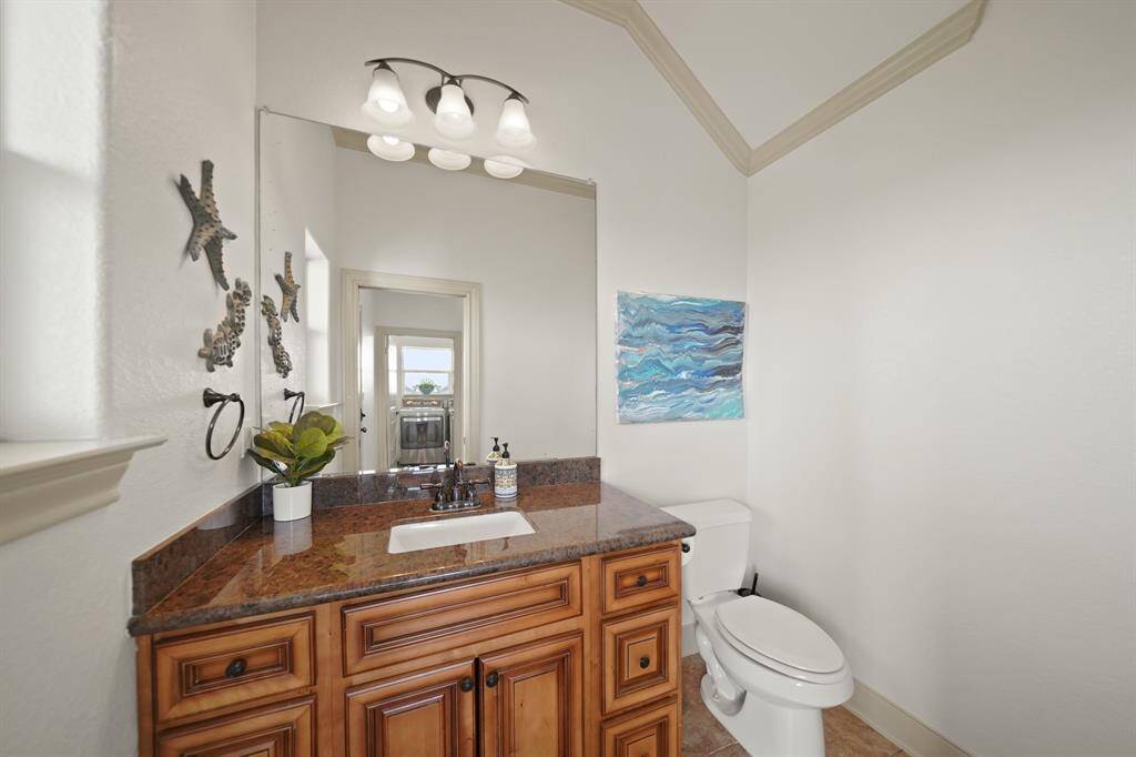 Coastal charm meets convenience in this half bath, featuring a granite vanity with rich wood cabinetry, updated fixtures, and beach-inspired accents.
