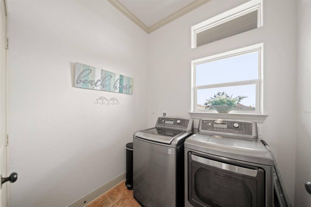 Light-filled laundry space with modern LG washer and dryer, decorative "Beach House" wall art, and tile floors—perfect for practical beach living.