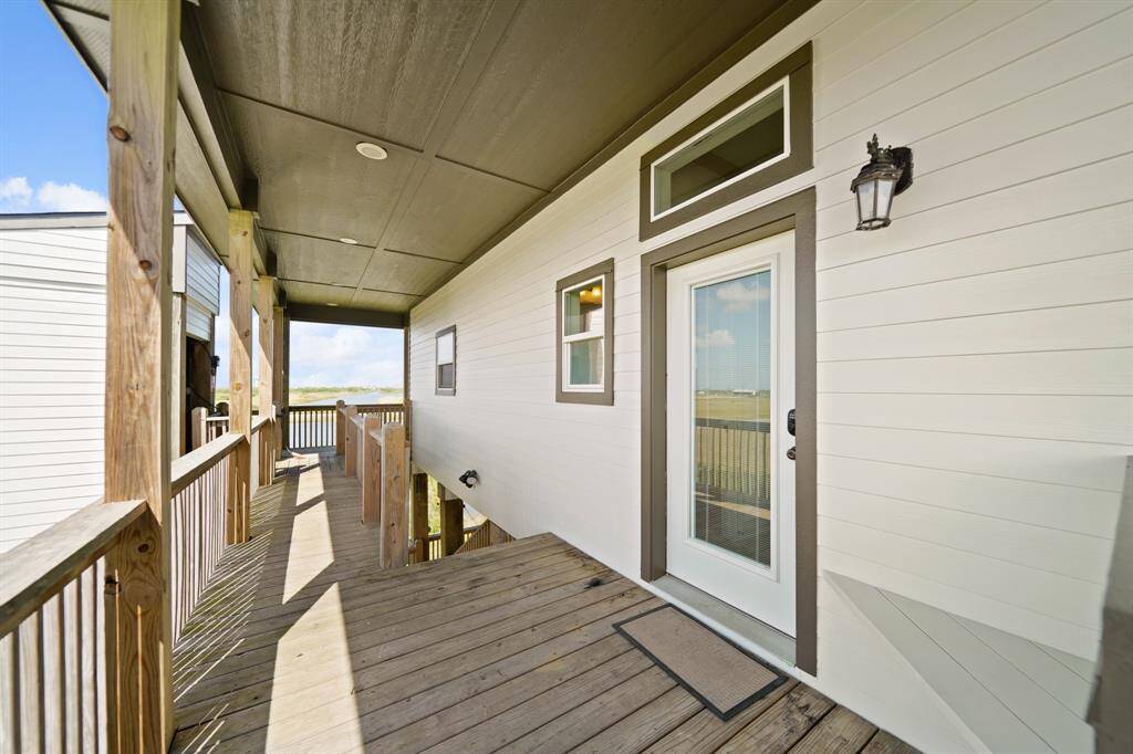 Elevated covered entry with wood decking and ramp access, offering beautiful water views and a seamless indoor-outdoor connection.