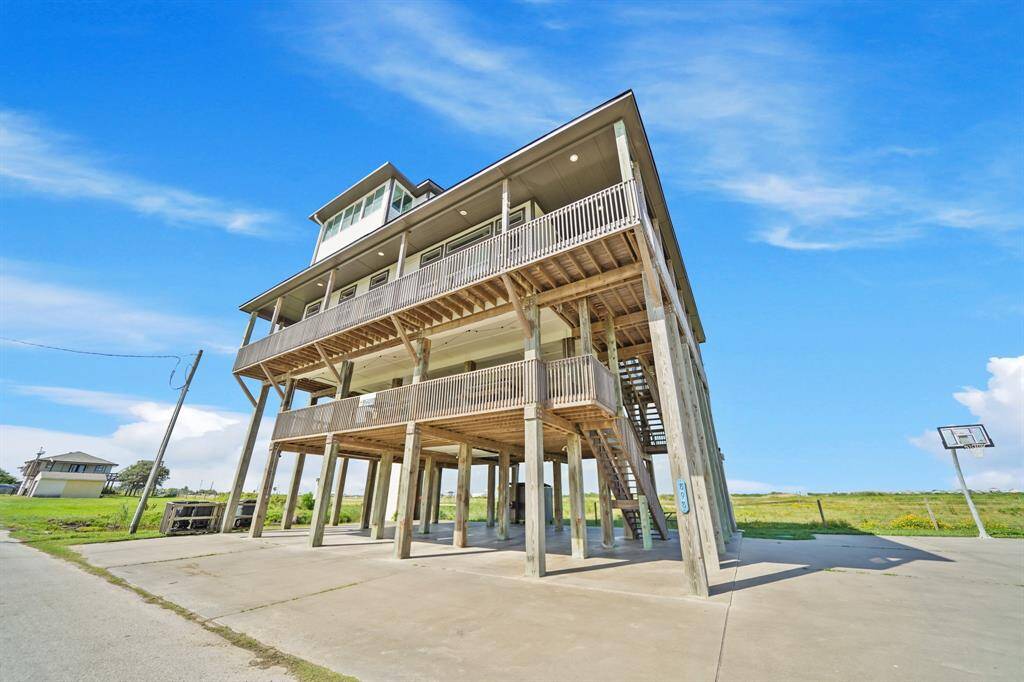 This elevated beach house makes a statement with its commanding multi-level design, tall pilings, and expansive wraparound decks.