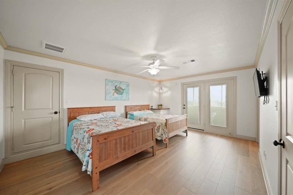 Beautifully furnished guest room with matching queen beds, coastal décor, private balcony access, and natural light.