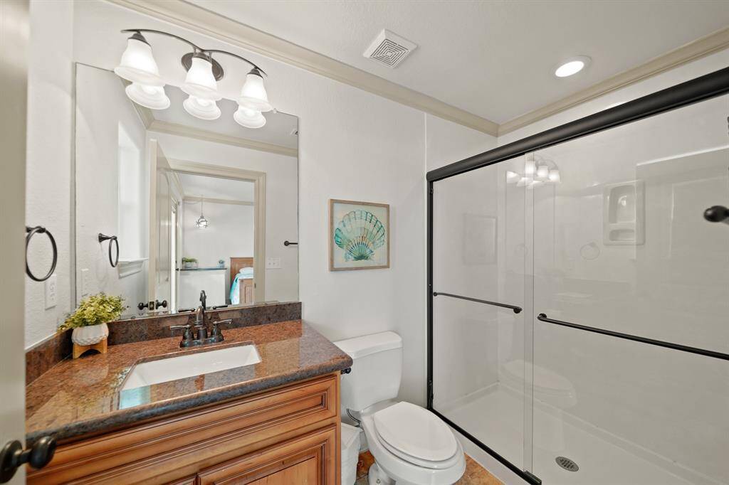 Stylish bathroom with dual glass-enclosed shower, granite counter, updated fixtures, and beachy design touches.
