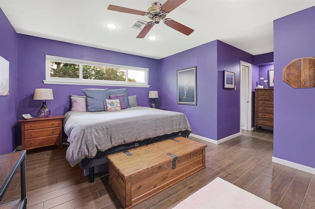 The delux Primary Bedroom features a ceiling fan, recessed lighting, wood-look ceramic flooring and natural light streams through a wide window. Connecting to the private bath and walk-in closet.
