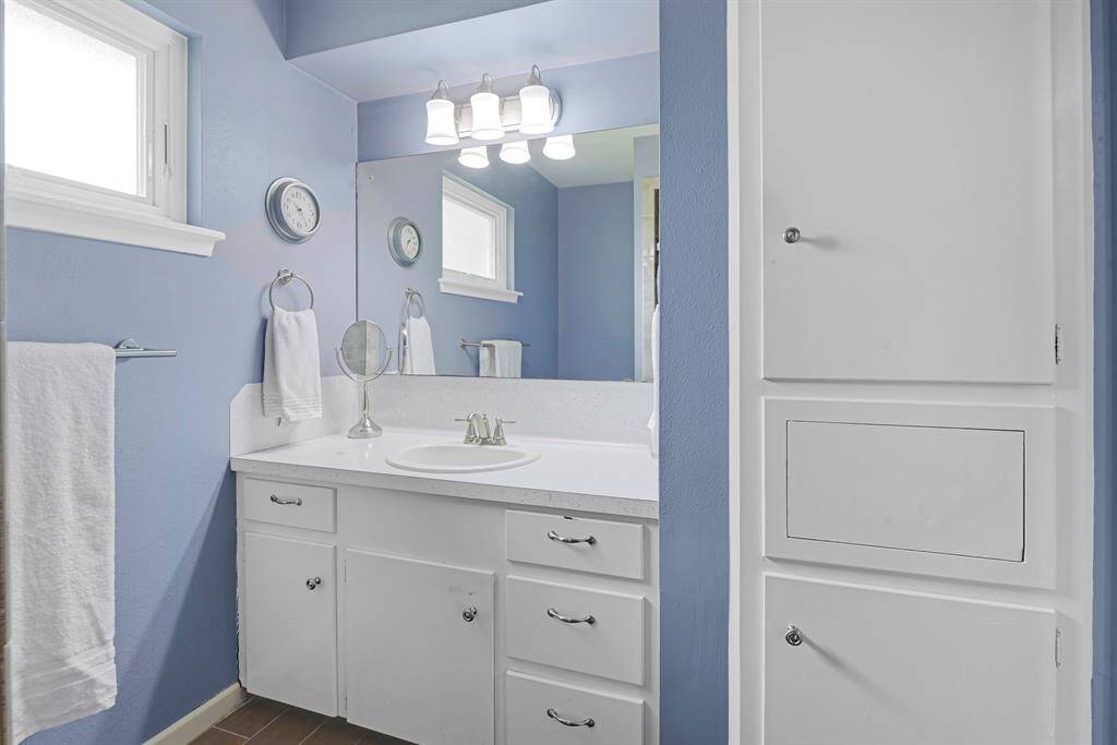 The primary vanity features updated lighting, a refresed shower, and a window that brings in natural light—along with ample storage for all your personal essentials.