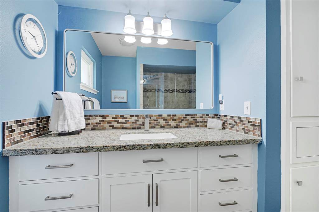 The Guest Bathroom boasts of newer cabinetry, granite counters with under-mount sink, glass tile backsplash and updated lighting.