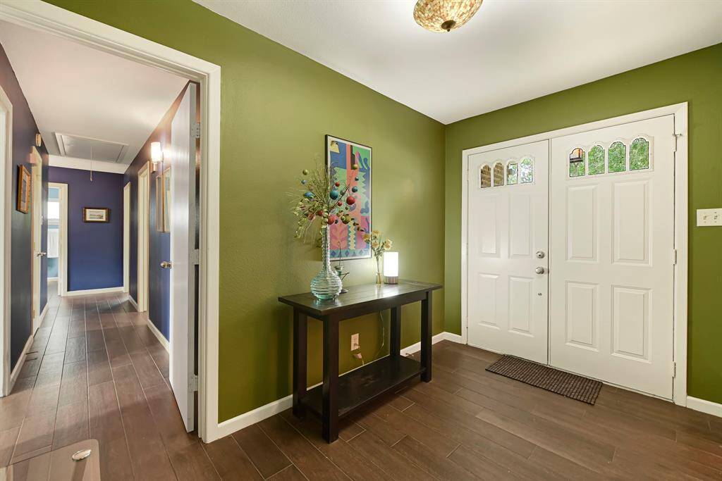 Welcoming Double Door Entryway with a Stylish, Warm Design. Decorative Ornate Chandelier and Glass Panels adds to the Uniqueness of this captivating Home.
