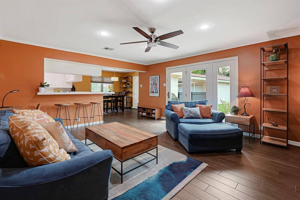 The open layout connects to the kitchen, breakfast room and breakfast bar providing more seating space, while large French doors lead to an outdoor area, enhancing the room's spacious and airy feel.