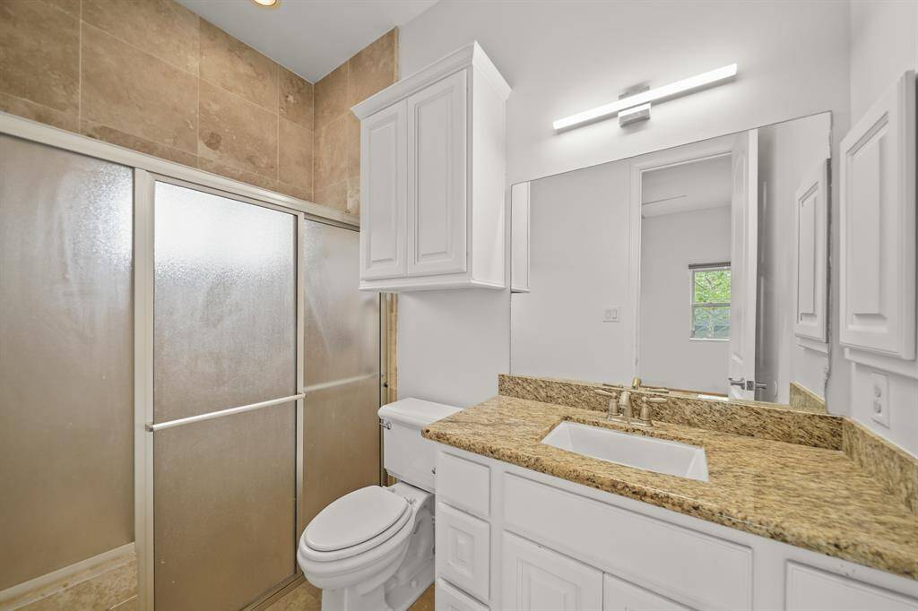The Bathroom to the EnSuite 4th Bedroom offers a Granite Topped Vanity, Kohler  Undermount White Porcelain Sink, Polished Nickel Faucet, White Painted Raised Panel Cabinets, Fresh Designer Paint, Kohler Commode, White Painted Wall Mounted Cabinet, and Travertine Tile Floors.  Also featured is a Walk in Shower with Travertine Tile Surround, Built in Bench, Rain Shower Head, Separate Shower Wand, and Sliding Glass Door Enclosure.