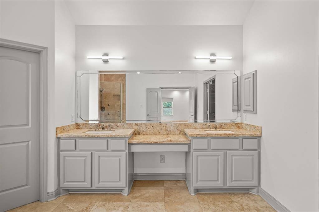 The Primary Bath features a Granite Topped Vanity, Dual Kohler Undermount White Porcelain Sinks, Polished Nickel Faucets, Grey Painted Cabinets/Drawers, Dual 3 Light Polished Nickel Light Fixtures, and Wall to Wall Mirror (with Beveled Edge).