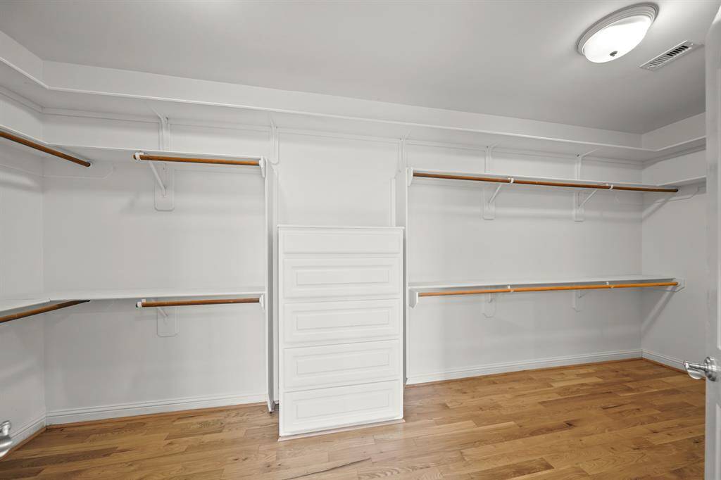 The Amazing Walk in Primary Bedroom Closet (Approximately 19'5" x 6'11") boasts Brand New (April 2025) Refinished Natural Hardwood Floors, Built in Dresser, Built in Shelves, Multiple Hanging Rods, Dual Flush Mount Light Fixtures, and Wall Mounted Dressing Mirror.